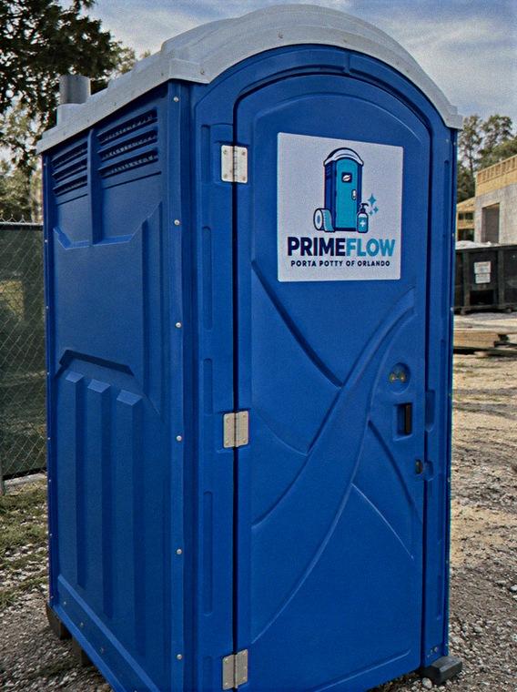 Blue portable restroom beside a chain link fence