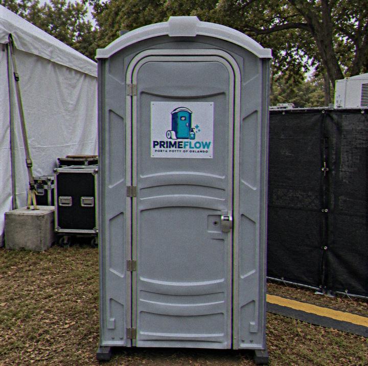 Portable restroom set up beside marquee tents at an outdoor event